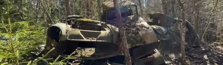 Obesiktigad bil på bilskrot som väntar på demontering och återvinning av reservdelar och metallmaterial.