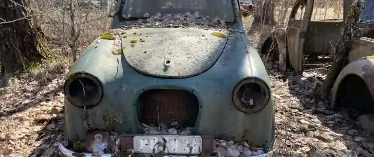 Obesiktigad bil på bilskrot där fordonet analyseras inför demontering och återvinning av reservdelar och metall.