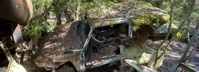 Obesiktigad bil på bilskrot där fordonet väntar på demontering och återvinning av reservdelar och metall.